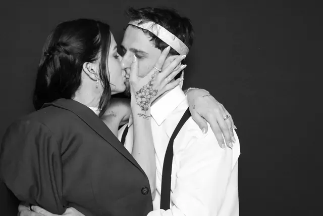 Couple sharing a kiss in front of a dark backdrop in a black-and-white Glam portrait.