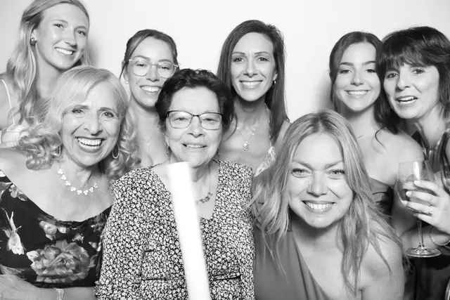 Large group of women smiling closely together in a black-and-white photo booth portrait.