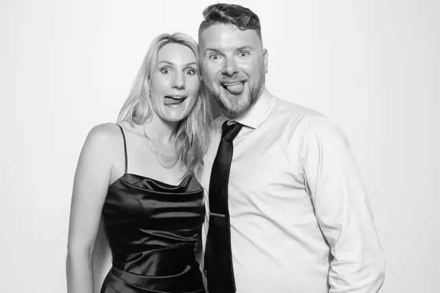 Two guests making playful faces in a black-and-white photo booth portrait.