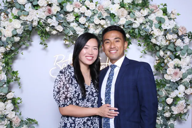 Guests enjoying a photo booth with a floral greenery backdrop, photo 1