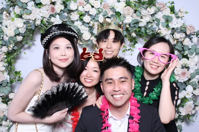 Guests enjoying a photo booth with a floral greenery backdrop, photo 2
