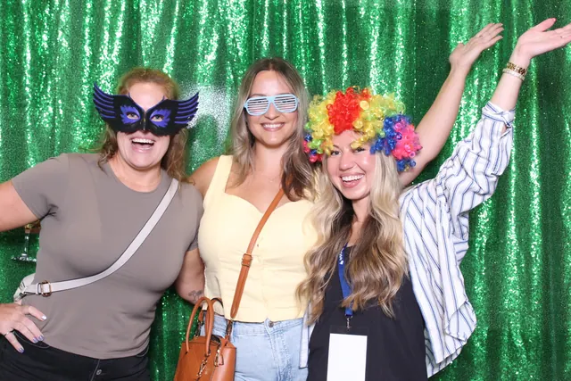 Guests enjoying a photo booth with a green backdrop, photo 1