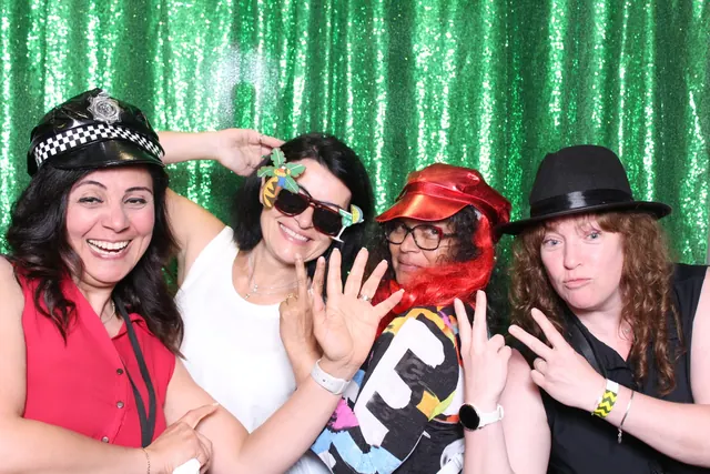 Guests enjoying a photo booth with a green backdrop, photo 2