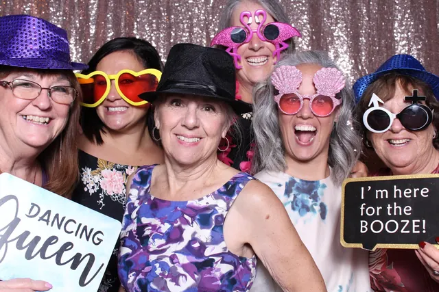 Guests enjoying a photo booth with a rose-gold sequin backdrop, photo 4