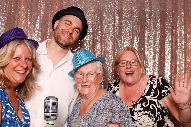 Guests enjoying a photo booth with a rose-gold sequin backdrop, photo 6