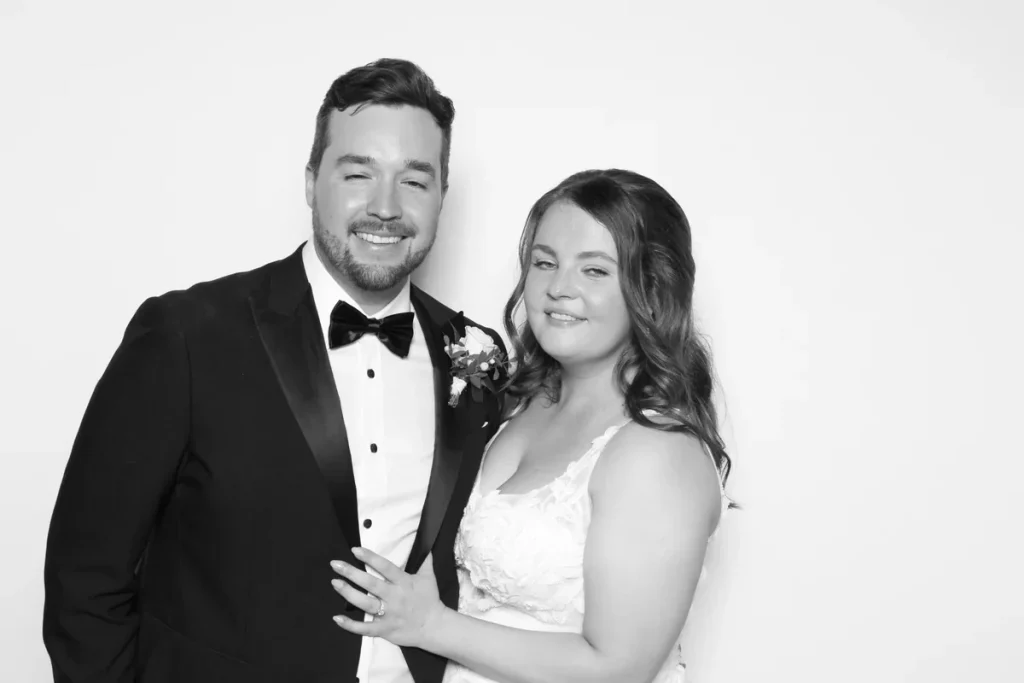 Rachel and Scott smiling together in a black-and-white wedding photo booth portrait
